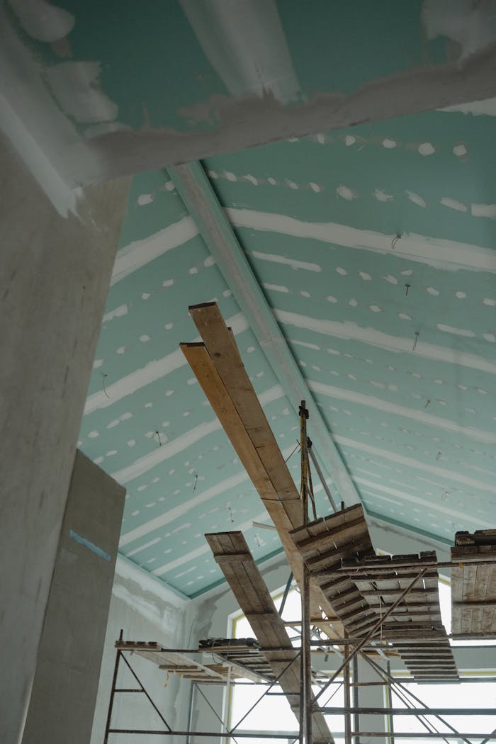 about-us-02 Scaffolding setup in an interior construction space with suspended ceiling boards and wooden planks.